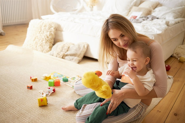 Baby Playing with the toys sitting on the lap of her mom