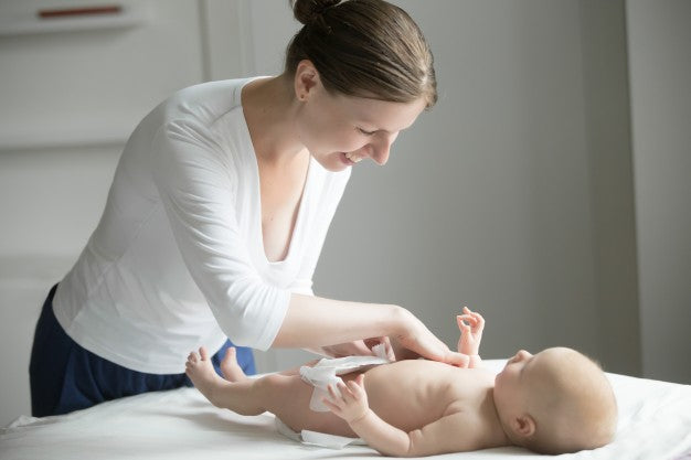 A smiling Women fixing diaper to a new born